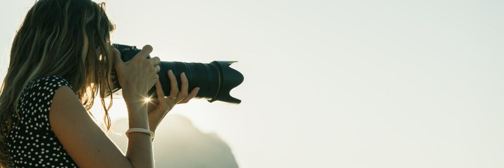Professional female photographer with zoom lens taking a photo